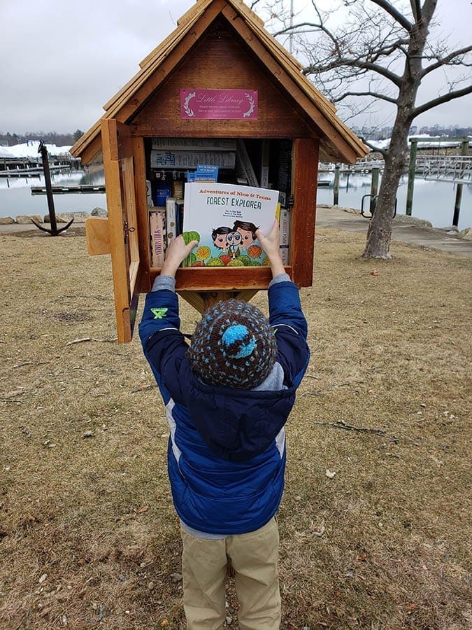 Ethan und sein Sohn werfen einige Exemplare einer Geschichte in die kleinen Bibliotheksboxen in der Stadt